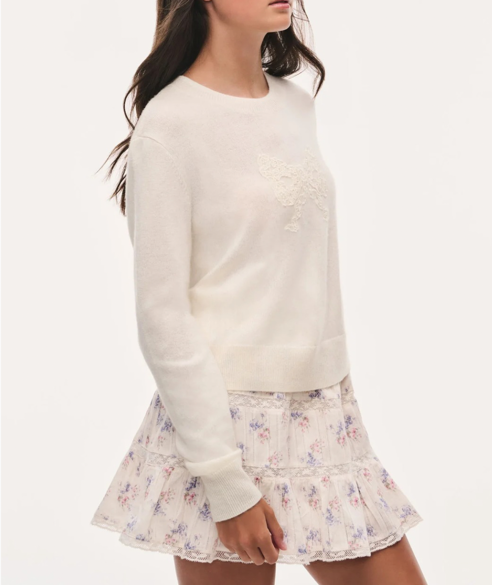 Side view of the LoveShackFancy Tween Zolee Lace Bow Pullover in Cozy Ivory with tonal lace bow, crew neckline, long sleeves, and ribbed trim.