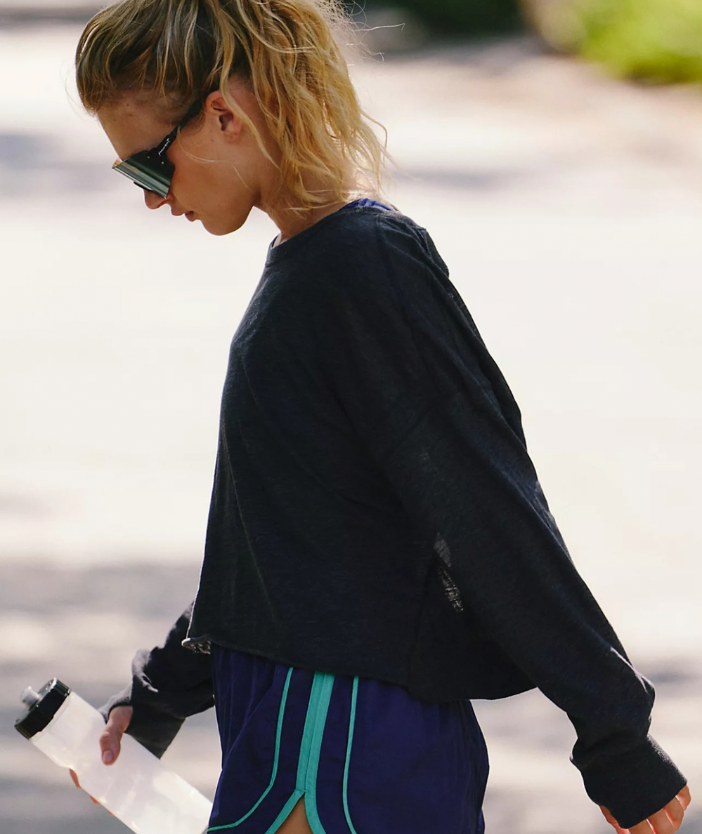 Side view of FP Movement My Time Long Sleeve Layer Tee in Black showing the slouchy fit, longer sides, and ribbed cuffs.
