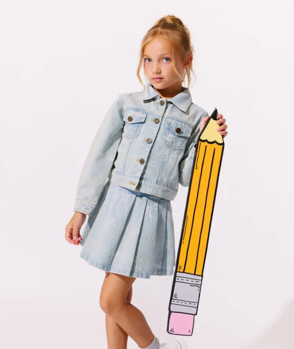 Model wearing the Lola & the Boys Tween Denim Sparkle Bow Jacket in light-wash denim with rhinestone bow embellishments and button-front closure.