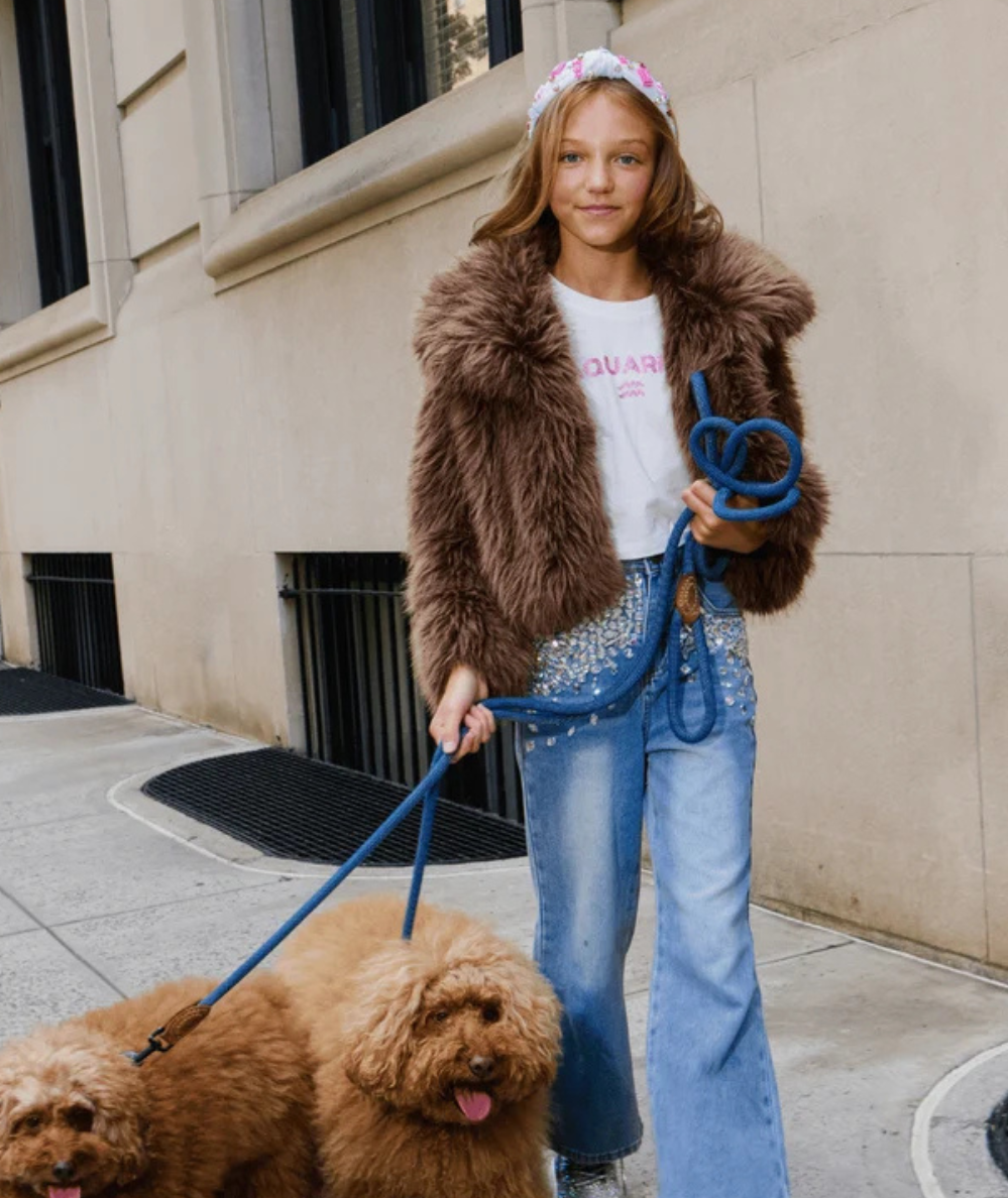 Model wearing the Lola & the Boys Tween Cozy Coco Faux Fur Jacket in brown with a fluffy oversized collar, long sleeves, and cropped hem.