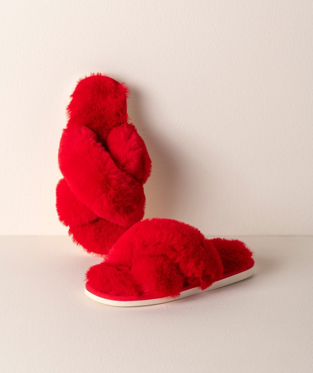 Pair of red plush Christina slide slippers with cushioned soles styled on a table by Shiraleah - CAKEWISH.