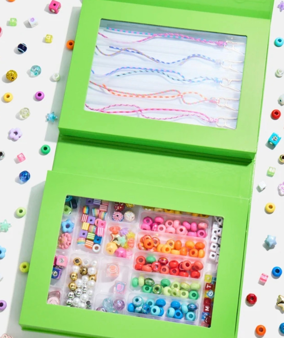 Open DIY bag charm kit with rainbow beads sorted in compartments and colorful paracord charm bases.