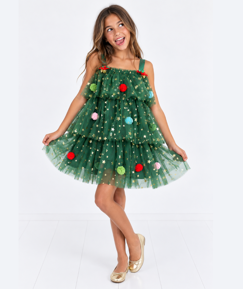 Girl making a silly face in the kitschy green starry tulle dress with colorful pom pom ornaments and gold flats by Lola + The Boys - CAKEWISH.