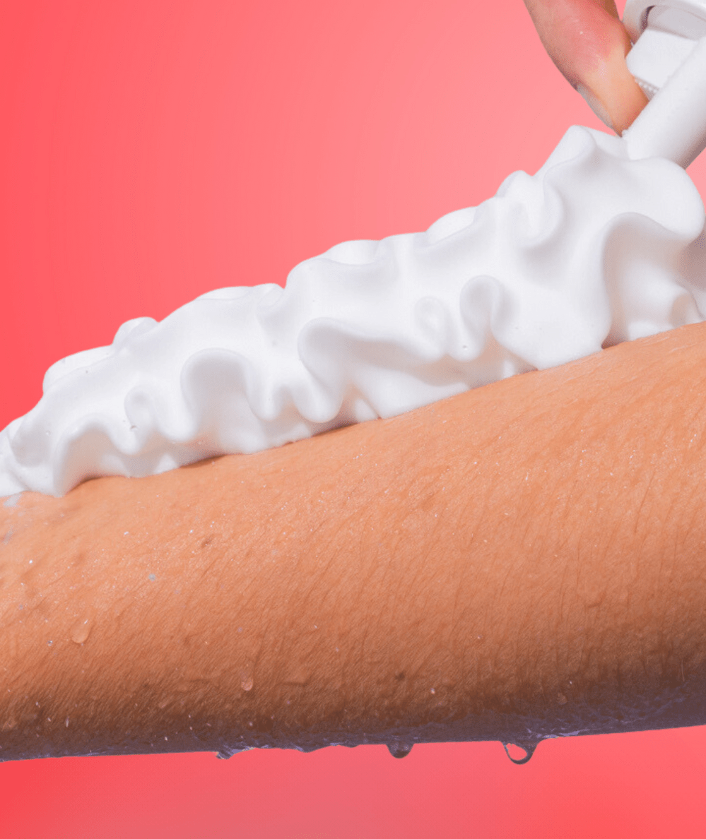 Thick white whipped body wash foam being applied to an arm, showing the fluffy shower foam texture by Sundae Body - CAKEWISH.